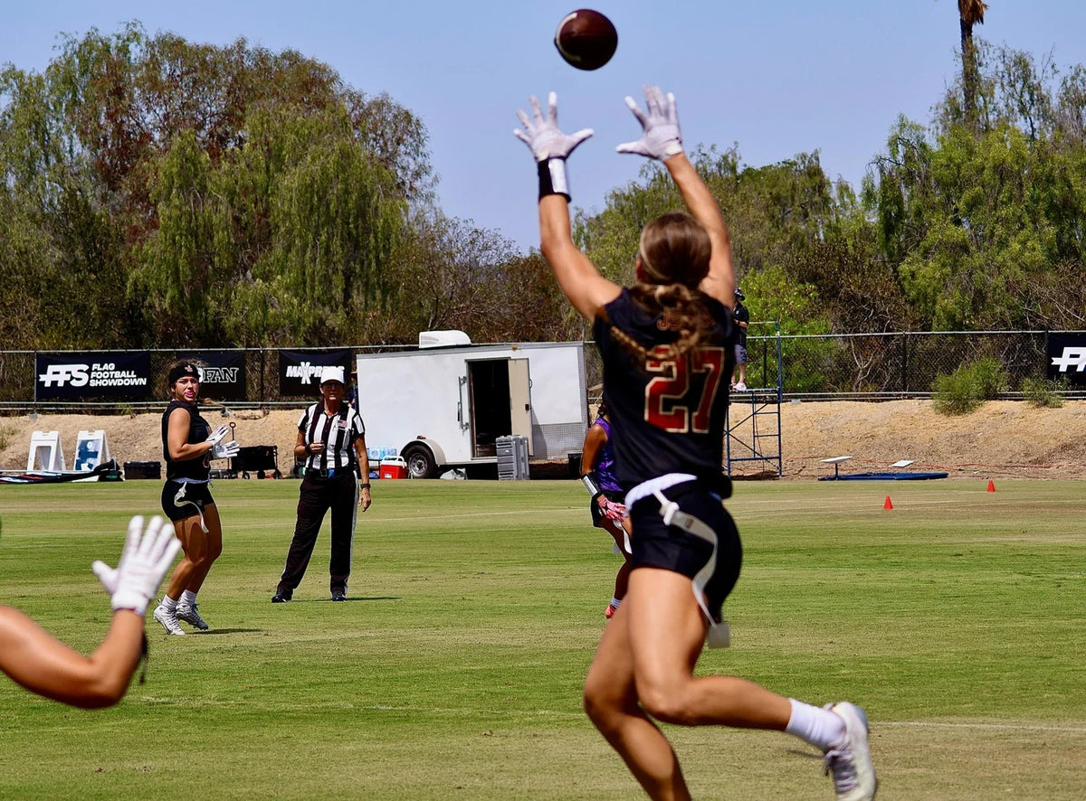Girls flag football receiver reaching for a pass during a high school tournament
